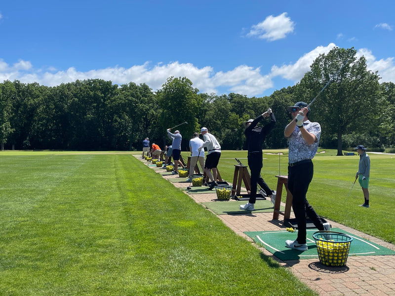 Golfers practicing at a driving range on a sunny day