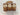 Three packages of Misericordia Cinnamon Sour Cream Bread on a wooden board with a speckled countertop background.