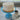 Coconut cake on a blue stand with a cup of coffee and saucer in the background.