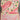 Number "2" shaped cake with pink frosting and floral decorations on a metallic surface.