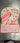 Number "2" shaped cake with pink frosting and floral decorations on a metallic surface.