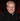 Priest wearing a black suit with a red cross pin on a formal event