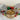 Decorative cookie tin with cookies, Christmas ornaments, and a festive lid on a white surface.