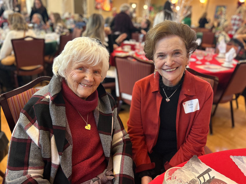 Two women smiling at a social gathering in an event space.