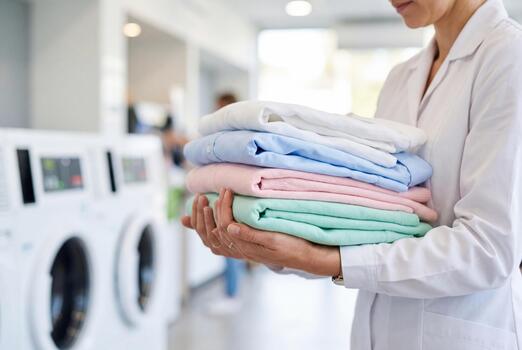 Person holding folded laundry in a laundromat
