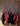 Group of people posing together in formal attire against a curtain backdrop