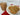Cookies on a plate and in a clear bag on a white surface with a red napkin.