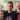 Three people posing together in a home setting. The central person is wearing a navy blue t-shirt with a white and red graphic that reads 'Independence Park' and features a stylized figure.