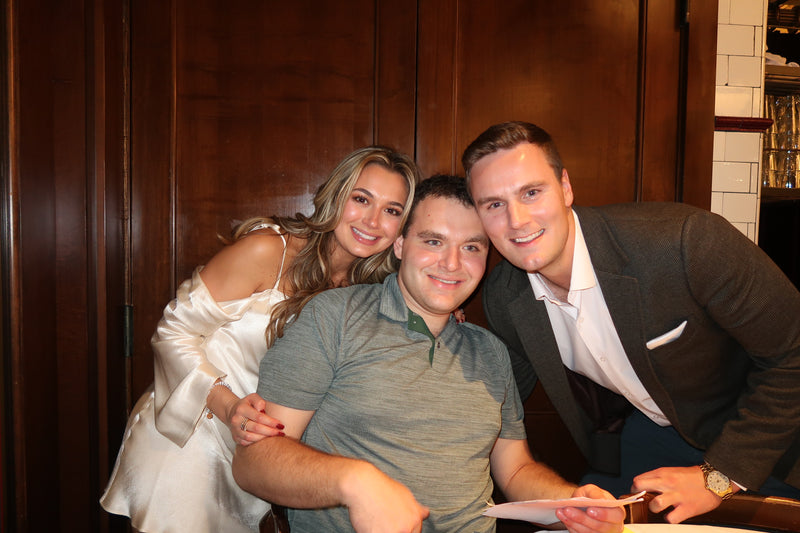Three people posing together in a formal setting with wooden paneling.