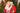 Two people in festive attire with a microphone against a Christmas tree background