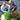 Two people, an older man and woman, are watering plants together outdoors.