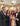 Group of people posing for a photo in an ornate room with chandeliers.