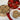Cookies in a gold tin with a heart-themed lid, some on a white plate, on a wooden surface.