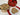 Cookies in a gold tin with a heart-themed lid, some on a white plate, on a wooden surface.