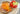 Bagel sandwich with lox and vegetables next to a bowl of fruit on a plate.