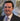 Man in a suit and tie standing indoors with decorative elements in the background